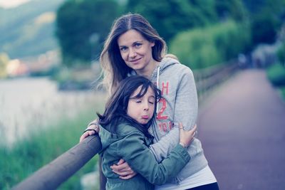 Portrait of mother with daughter standing on bridge