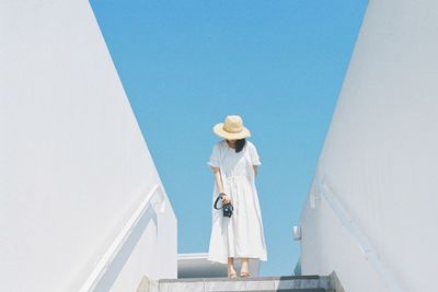 Low angle view of woman against clear blue sky