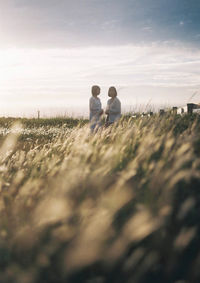 Rear view of couple on field against sky