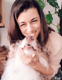 Portrait of smiling woman holding dog at home