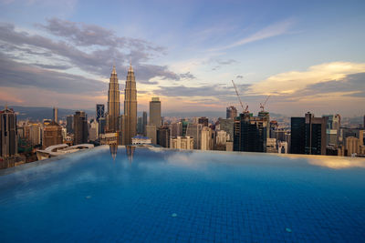 Infinity pool against petronas towers during sunset in city