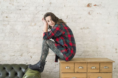 Portrait of a young woman sitting on a cabinet