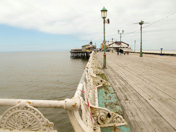 Pier on sea against cloudy sky