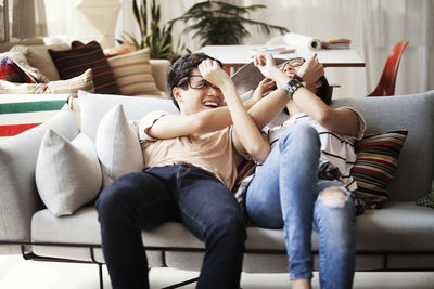 Playful multi-ethnic couple reclining on sofa at home