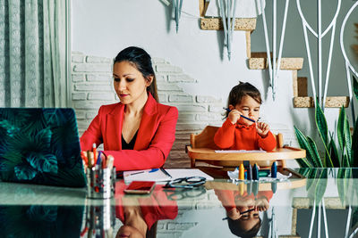 Young executive woman working from home while taking care of her young daughter