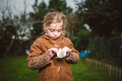 Girl making origami while standing on land