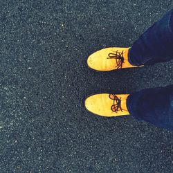 Low section of man wearing yellow shoes while standing on wet road