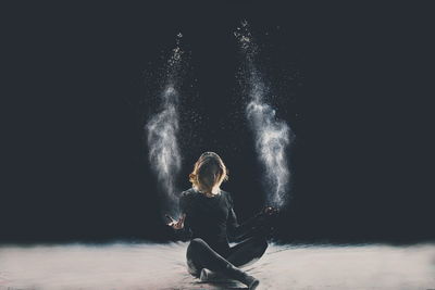 Creative portrait of young woman against black background