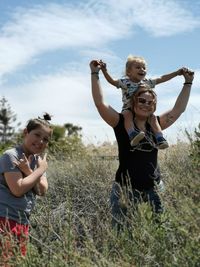 Happy family standing amidst plants against sky