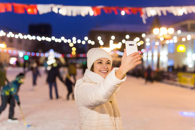 Rear view of woman standing in city at night