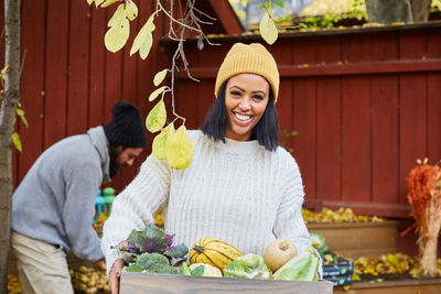 Portrait of happy woman with food basket standing in yard