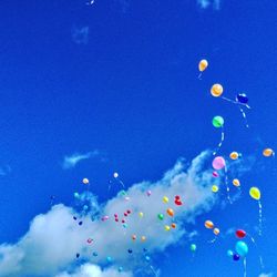 Low angle view of colorful balloons against blue sky