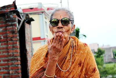 Senior woman wearing sunglasses blowing kiss