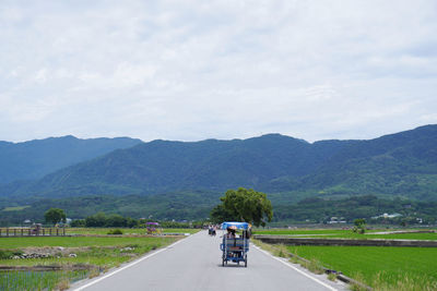 Car on road by mountains against sky