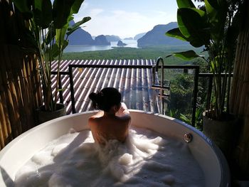 Rear view of woman relaxing in bathtub