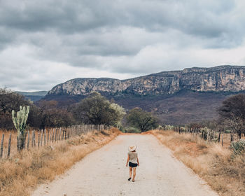 Unidentified tourist walking along a rural road with serra de bom sucesso in the background, bahia,