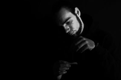 Portrait of man making face against black background