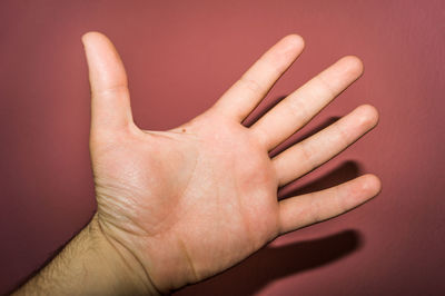Close-up of human hand gesturing against brown background