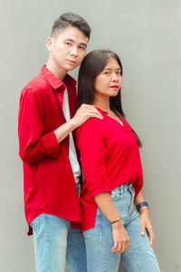 Portrait of smiling couple standing against wall