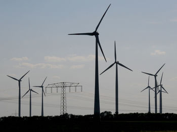 Wind turbines on field against sky during sunset