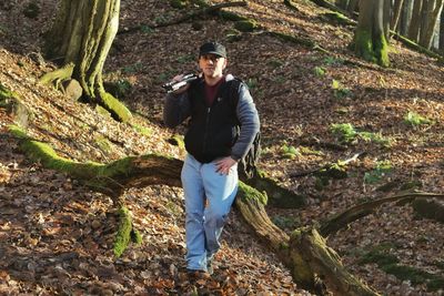 Portrait of man with tripod and camera in forest