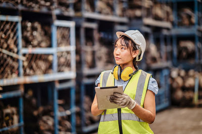 Confident female engineer looks at the machine parts according to the sheet on the tablet