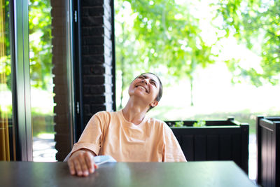 Woman looking away while sitting on table