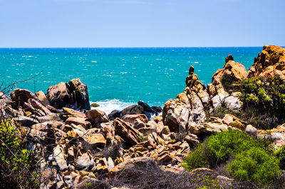 Rock formations by sea against clear blue sky