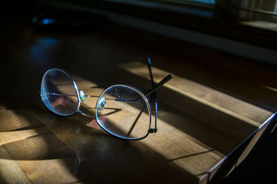 High angle view of sunglasses on table with shade of blinds.