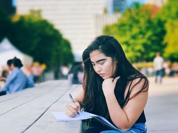 Young woman looking down while sitting outdoors