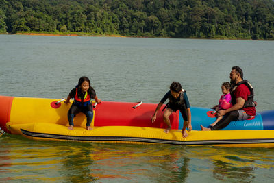 Family on boat in lake against trees