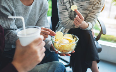 Closeup image of friends drinking and eating potato chips together