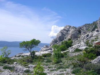 Scenic view of sea by mountain against sky