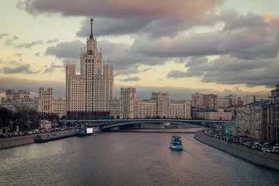 View of buildings at waterfront against cloudy sky