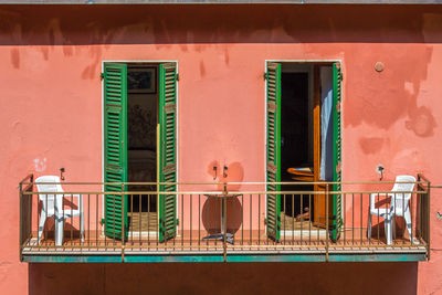 Colorful pink building with terrace. symmetry with colours, chris and shutters. italy 