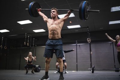 Amputee athlete picking barbell with people cheering in background at gym