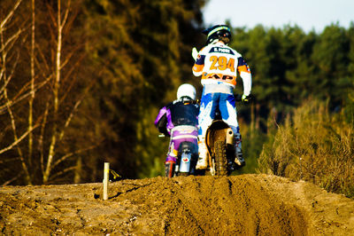 Rear view of man riding motorcycle on field