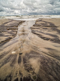 Tidal watercourse and marks in wet sand on the beach