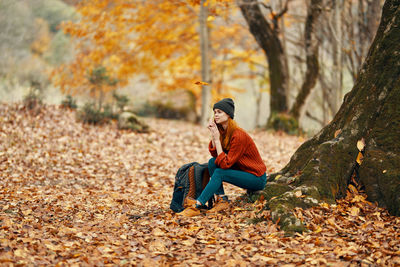 Young woman sitting on leaves during autumn