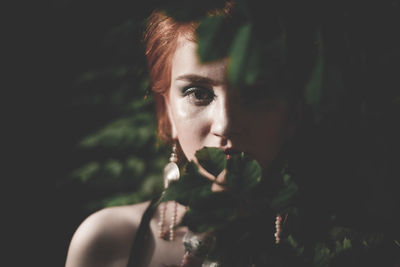 Close-up portrait of young woman amidst leaves