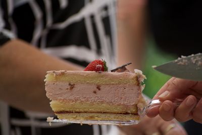 Cropped image of hand holding strawberry cake slice