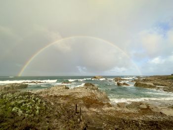 Full rainbow arch over pacific ocean wide view from coast on rainy morning
