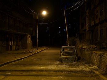 Car on street by illuminated buildings at night