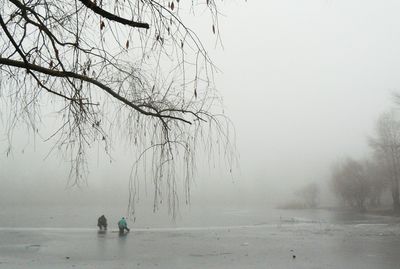 People standing on frozen sea against sky during winter
