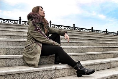 Side view of young woman sitting on staircase