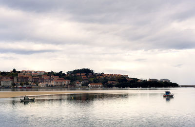 Scenic view of river by buildings against sky