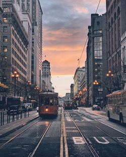 Railroad tracks in city against sky during sunset