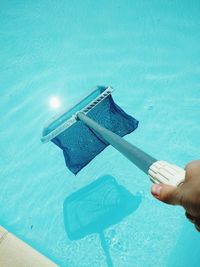 Cropped image of person cleaning swimming pool by net
