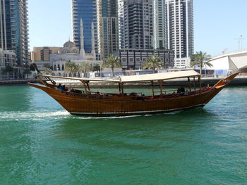 Boats moored in sea against buildings in city