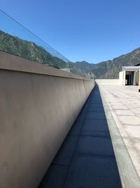 Footpath amidst buildings against clear blue sky